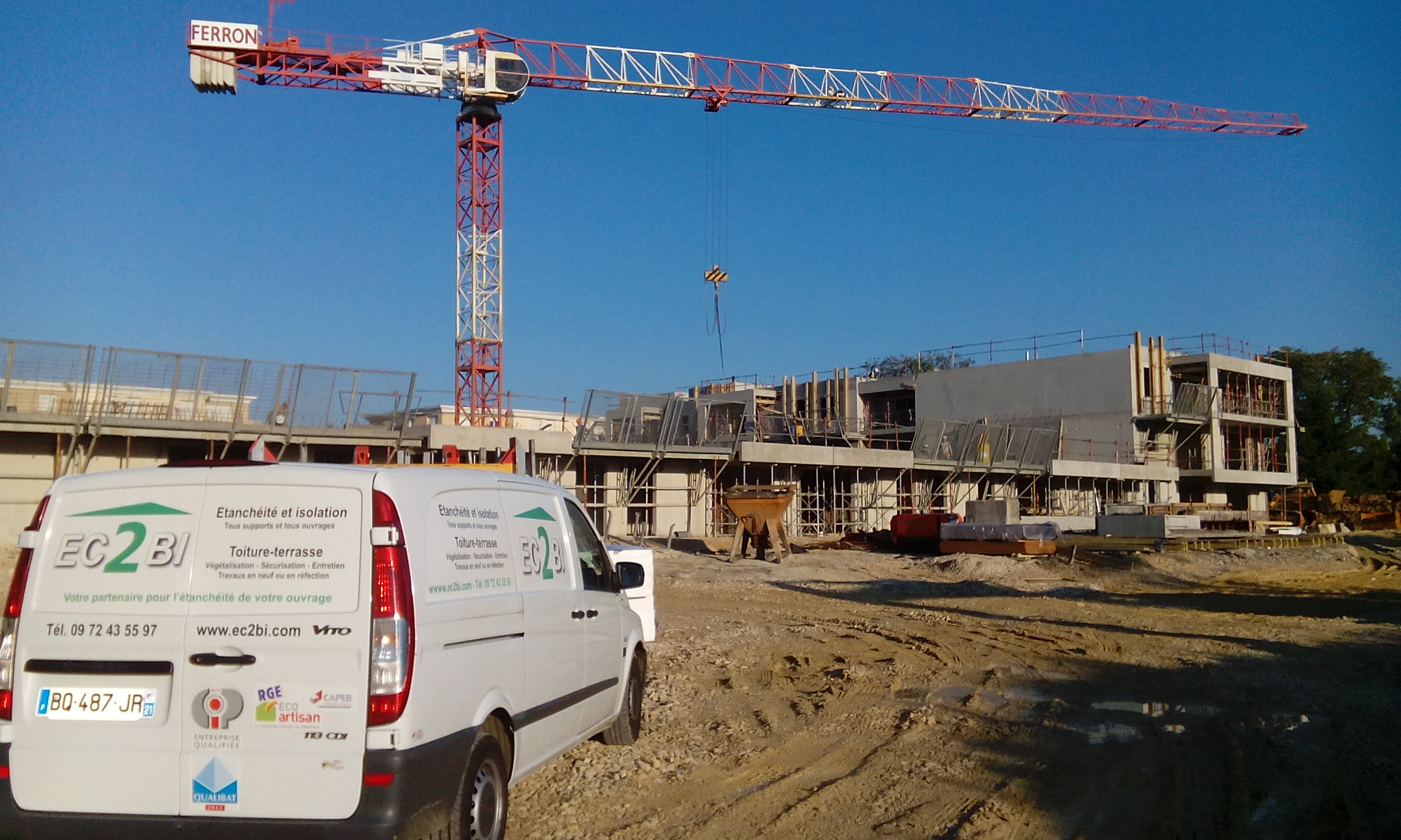 Véhicules EC2BI devant un chantier de construction, avec grue.